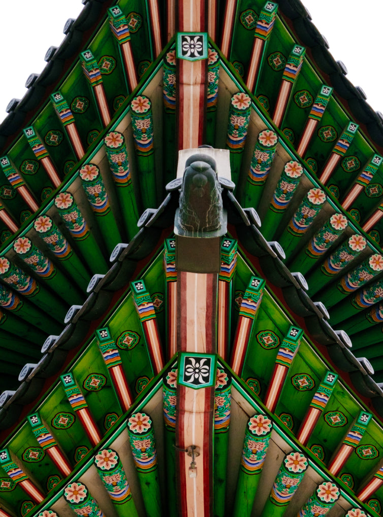 Detailed view of an intricately painted Korean palace ceiling with vibrant green and red wooden beams.