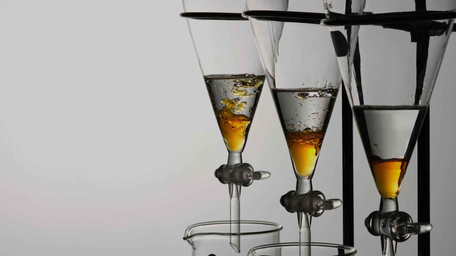 Glass funnels containing golden liquid in a laboratory setting, representing scientific beauty formulations.