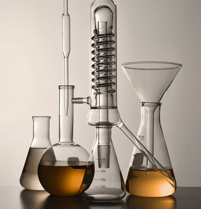 Three separatory funnels containing golden liquid forming distinct layers during an extraction process. Beakers are placed below, showcasing a precise laboratory extraction method.