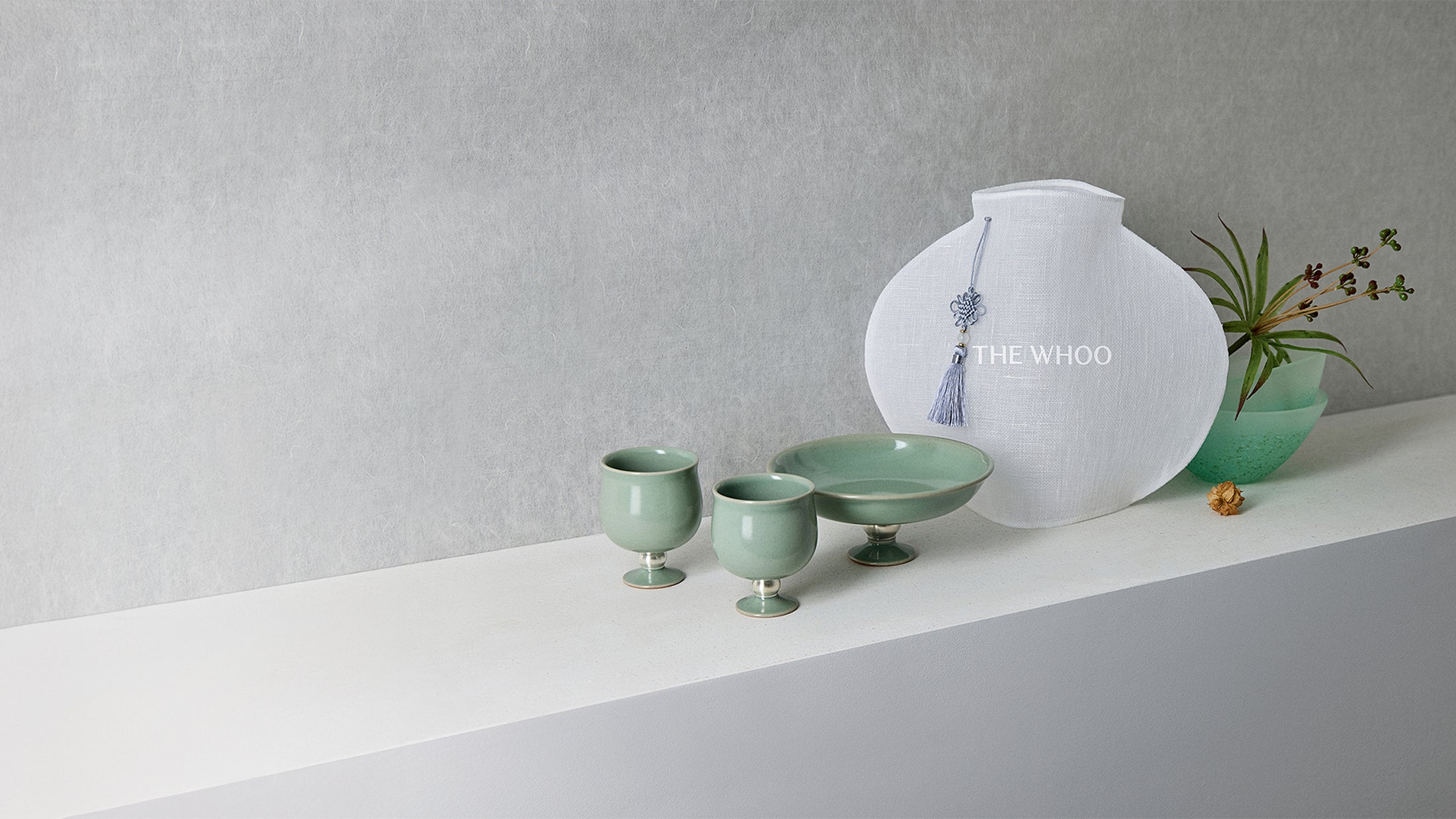 THE WHOO Imperial Youth collection products displayed on a soft mint-green silk drape with golden phoenix-inspired accents.