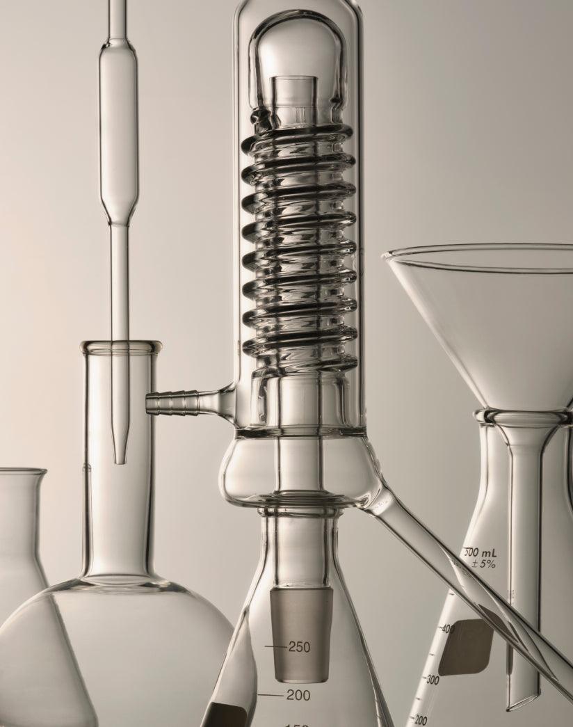 A transparent glass apparatus with multiple tubes and flasks connected for advanced skincare formulation research.